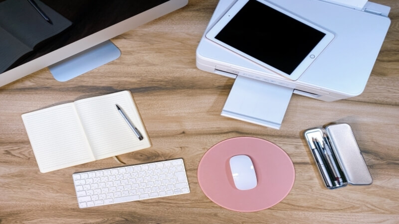 デスクにモニター、キーボード、ノート、プリンターが置いてある