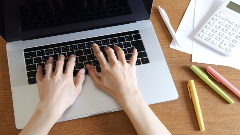 ノートパソコンのキーボードに手を置いている様子