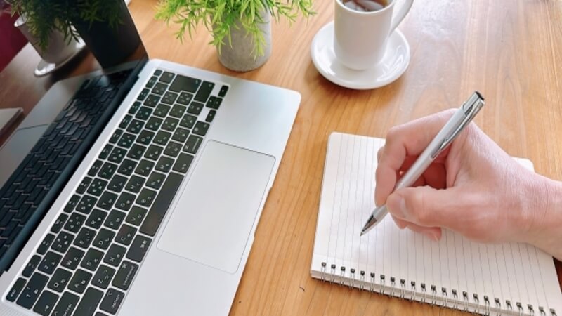 パソコンを開いてノートにメモしている様子